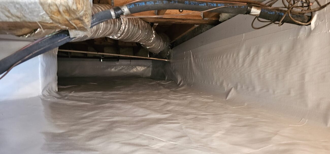 A clean, sealed crawl space with plastic encapsulation, visible ductwork, pipes, and wooden beams overhead.