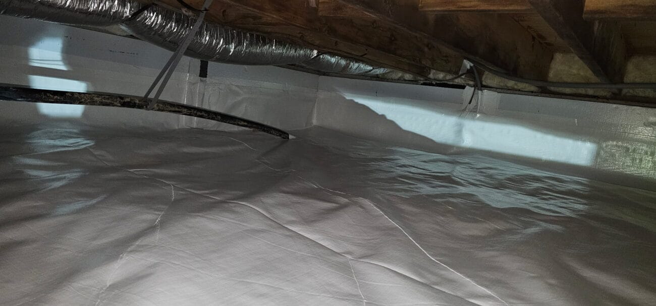Crawl space with white plastic vapor barrier lining the floor and walls, exposed ductwork, pipes, and wooden ceiling beams visible above.